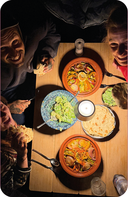 Friends sharing tajine, salad and fresh bread around a candle-lit table