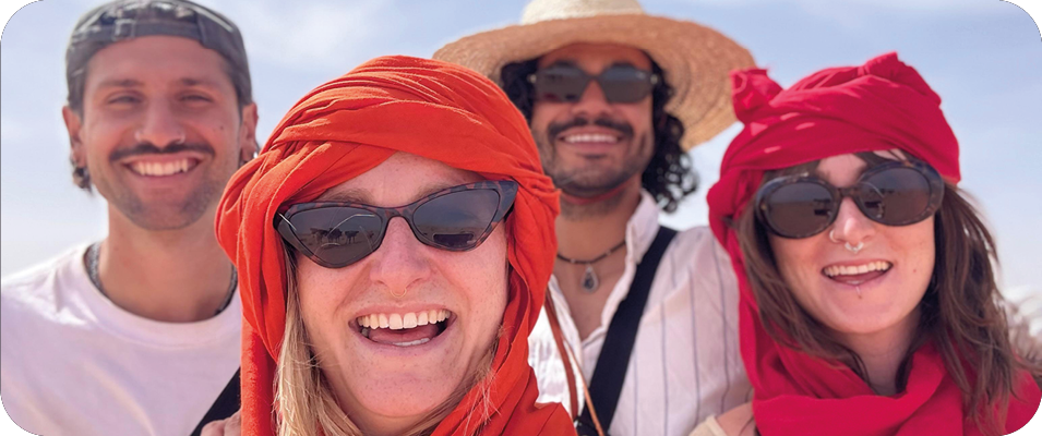 Vier Freunde mit roten Kopftüchern lachen in der Wüstensonne