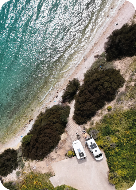 Zwei Campervans an einem türkisblauen Strand aus der Vogelperspektive