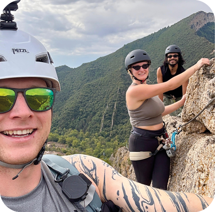 Drei Freunde lächeln beim Klettersteig in den Bergen